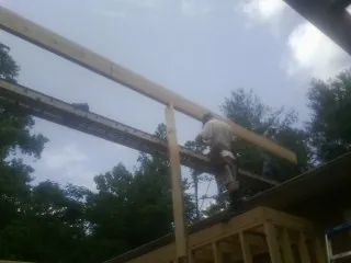 Carpenter setting a ridge beam over a new addition frame — Ice Dam Removal by Roofing Brothers in Woodmere