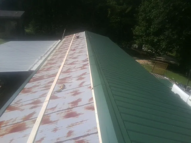 Old rusted panels beside newly installed green metal roofing — Wind Damage Roof Repair by Roofing Brothers in Woodmere