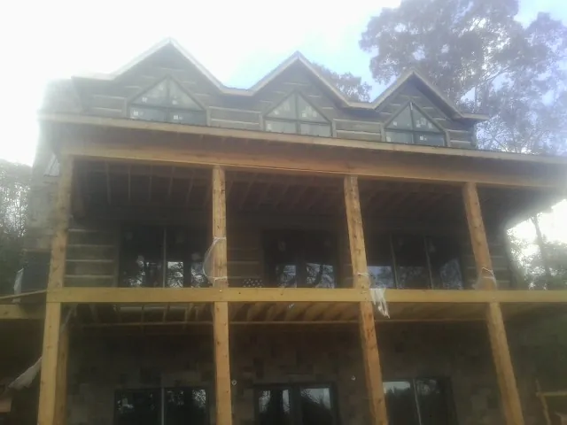 Dormers and porch framing on a large log home under construction — Roof Coating work by our crew in Woodmere