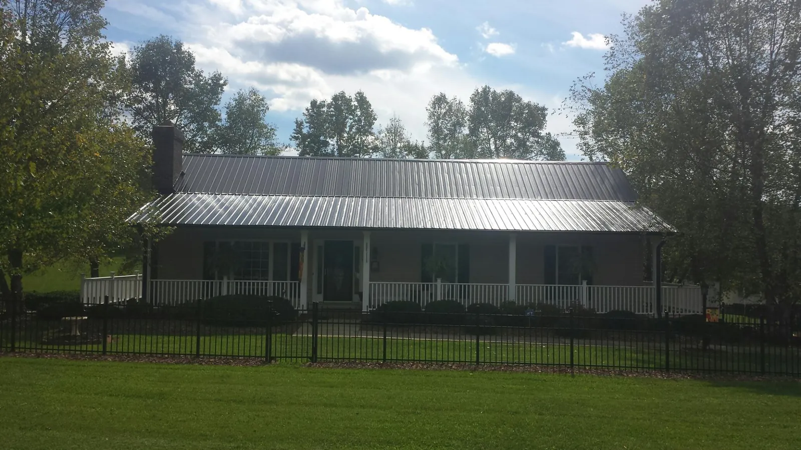 Gray metal roof on a brick ranch with a full width front porch — Gutter Guard Installation work by our crew in Woodmere